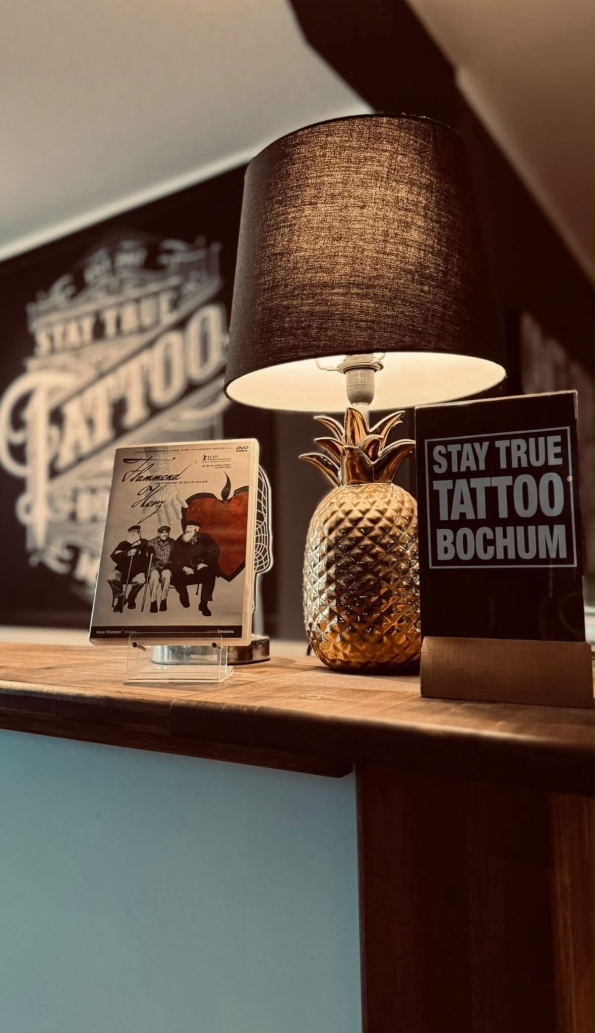 Empfangstresen im Stay True Tattoo Studio Bochum mit Lampe und Logo an der Wand