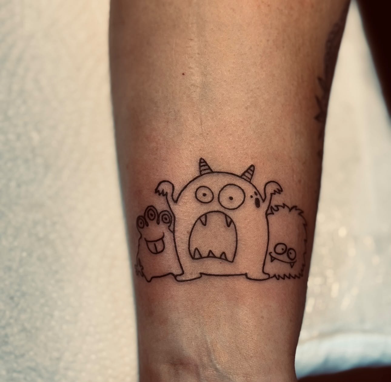 Kleine Monster im Linienstil am Unterarm